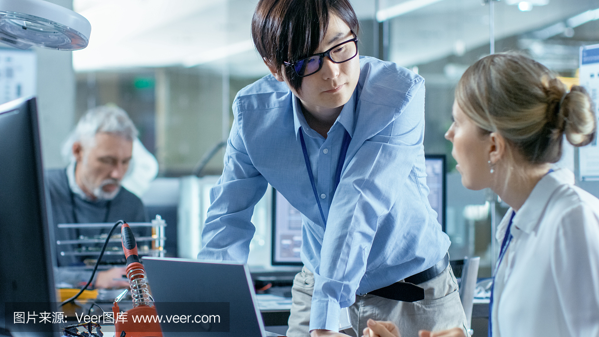 女計(jì)算機(jī)科學(xué)家用綠色屏幕模型連接電路板到她的筆記本電腦。她在先進(jìn)技術(shù)實(shí)驗(yàn)室工作。